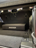Side view of the Down-Firing CompRT Kicker subwoofer enclosure installed in the trunk of a Jeep, highlighting the thin-profile design and optimal trunk space utilization