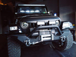 Black Jeep featuring a TJ American Soundbar with white LED ring lights installed, showcasing a custom audio and lighting setup.