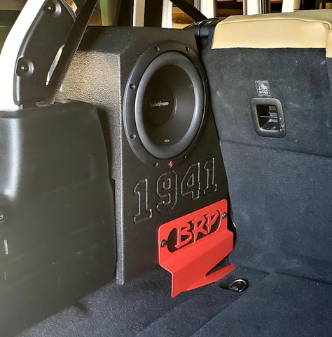 Rockford Fosgate Prime "R2D2" - Single BRP JL/JLU subwoofer installed in the rear wheel well of a Jeep Wrangler, secured with a red BRP stabilizer plate screwed into the subwoofer box for stability